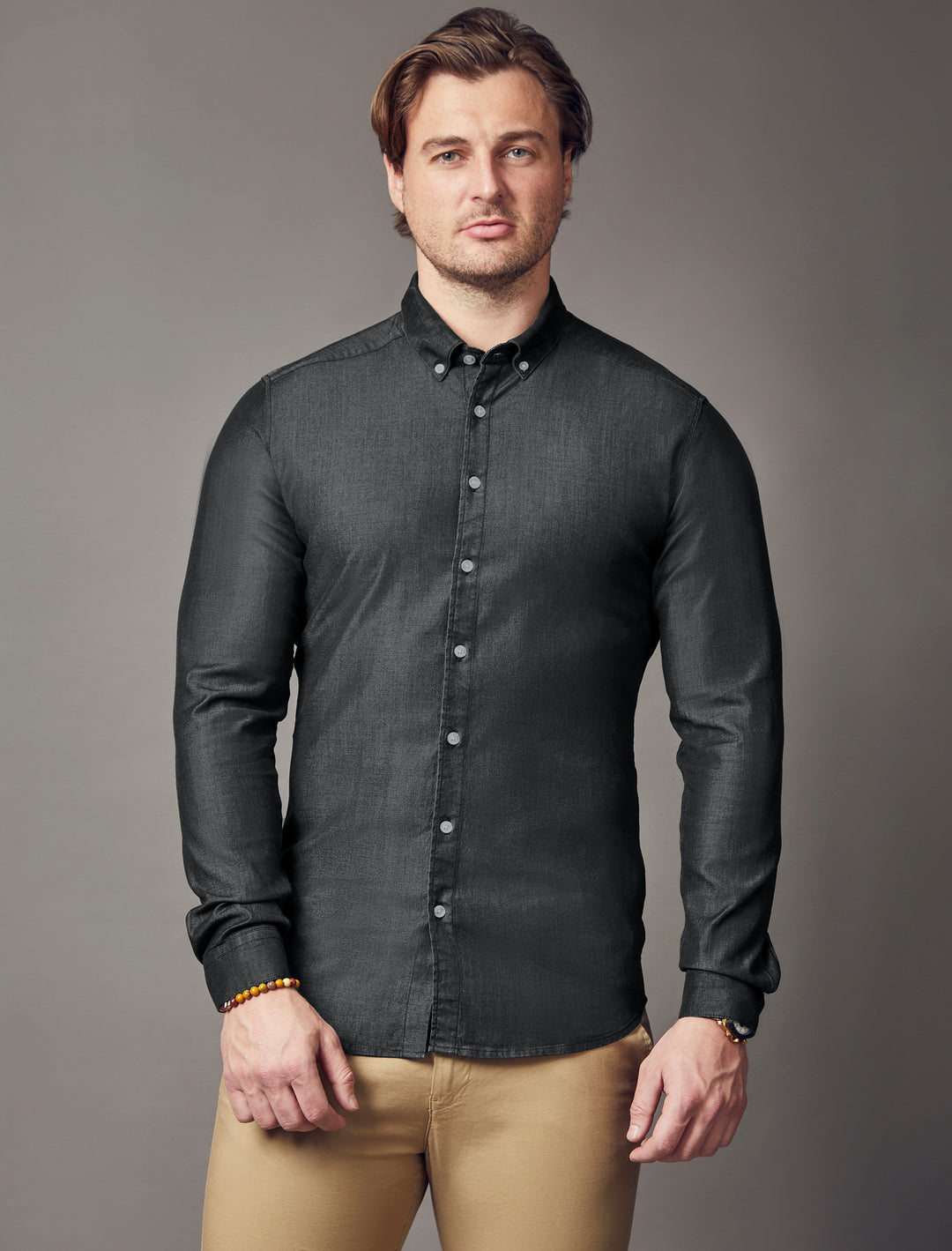 A men's black denim shirt designed with a tapered and muscle fit to accentuate a well-defined silhouette, offering a flattering and custom-tailored appearance.
