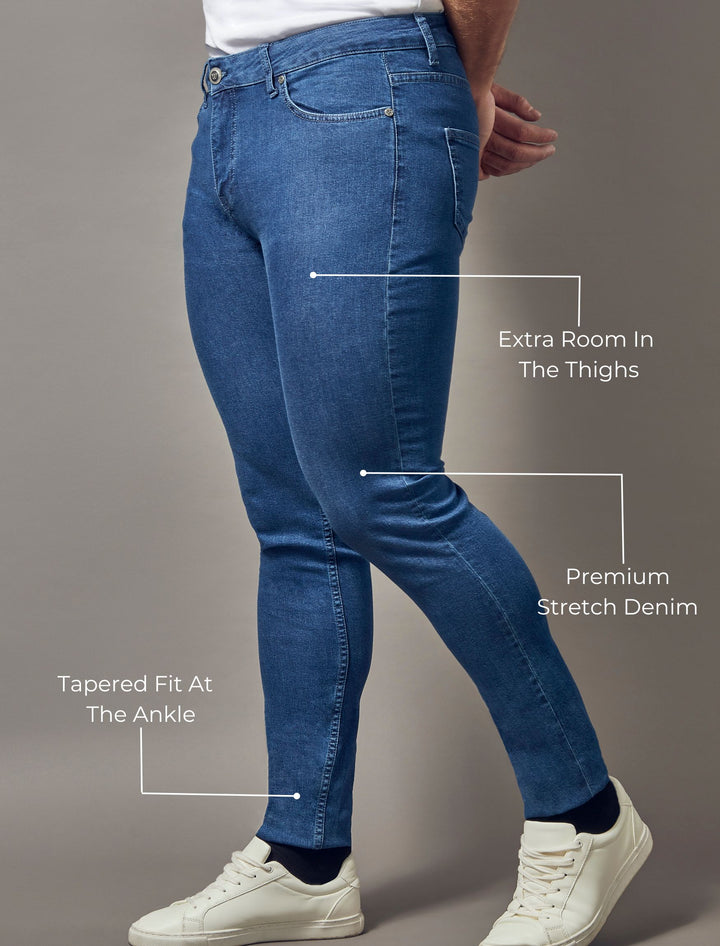 Tapered Menswear's mid-wash blue jeans, tailored for a muscle fit and emphasizing both the tapered style and premium quality.