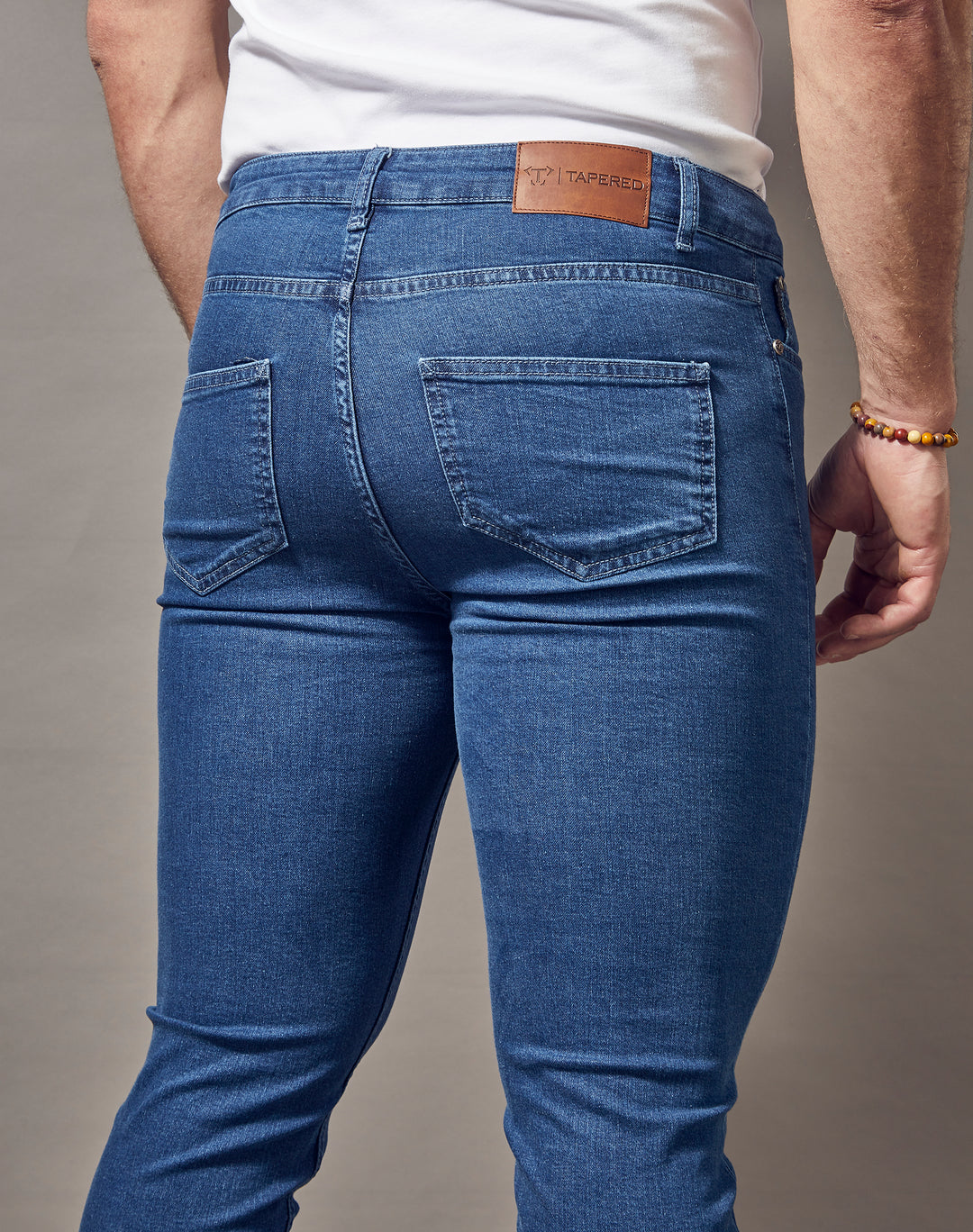 Mid-wash blue jeans with a muscle fit from Tapered Menswear, featuring a tapered design and exceptional quality.